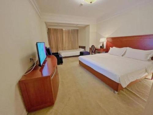 a hotel room with a bed and a television in it at Changshu Jinling Tianming Grand Hotel in Suzhou