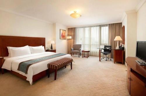a hotel room with a bed and a desk and a television at Changshu Jinling Tianming Grand Hotel in Suzhou