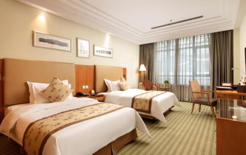 a hotel room with two beds and a desk at Changshu Jinling Tianming Grand Hotel in Suzhou