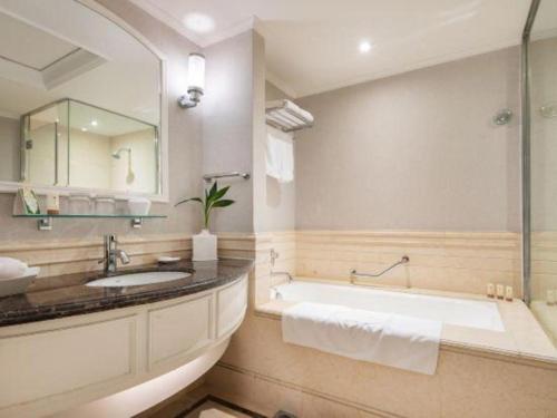a bathroom with a tub and a sink and a mirror at Changshu Jinling Tianming Grand Hotel in Suzhou