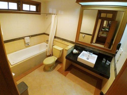 a bathroom with a tub and a toilet and a sink at Purnama Hotel in Malang