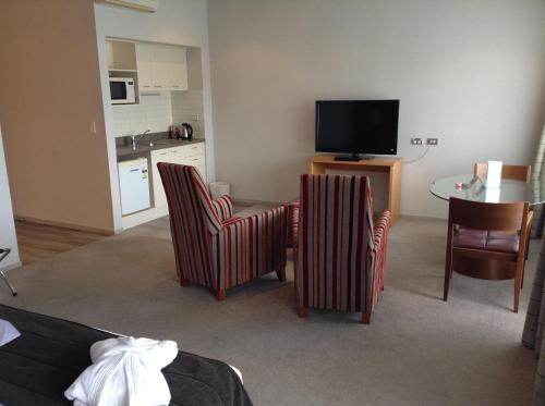 a living room with two chairs and a table and a television at Waipuna Hotel & Conference Centre in Auckland