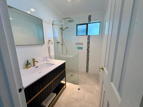 Un baño con lavabo y ducha con espejo. en Broadwater Beach Cottage, en Broadwater