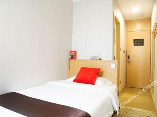 a bedroom with a red pillow on a white bed at Cozy Hotel Xiamen in Xiamen