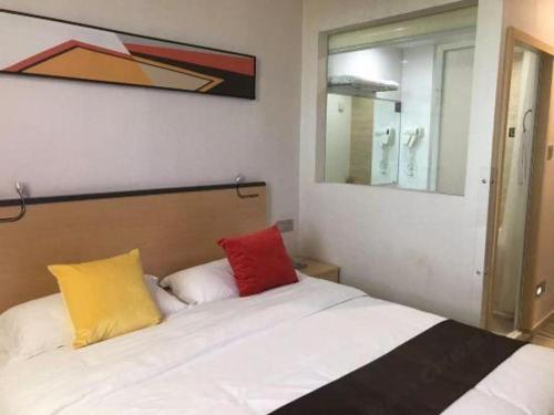 a bedroom with a white bed with two colorful pillows at Cozy Hotel Xiamen in Xiamen