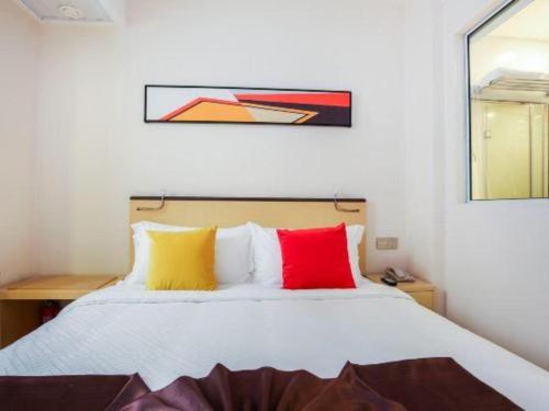 a bedroom with a white bed with colorful pillows at Cozy Hotel Xiamen in Xiamen