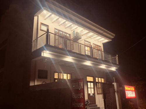 a tall white building with a balcony at night at Vishram Guest House in Jhājra