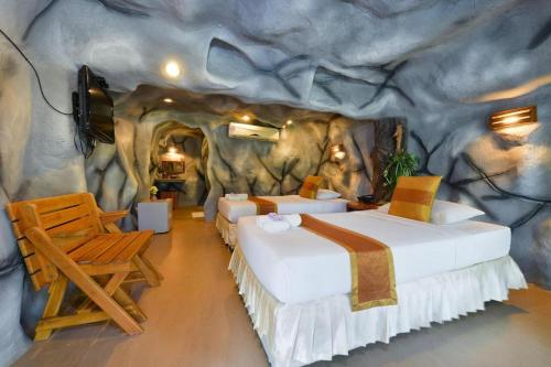 Zimmer mit 3 Betten in einer faux rock wall in der Unterkunft Had Ban Din Resort in Ban Nong Pru