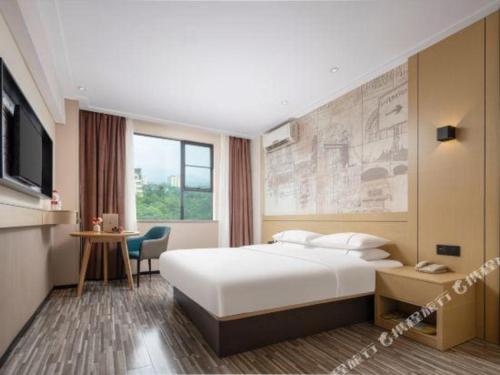 a hotel room with a bed and a desk and a tv at City Comfort Inn Liuzhou Beique Road Huang Village in Liuzhou