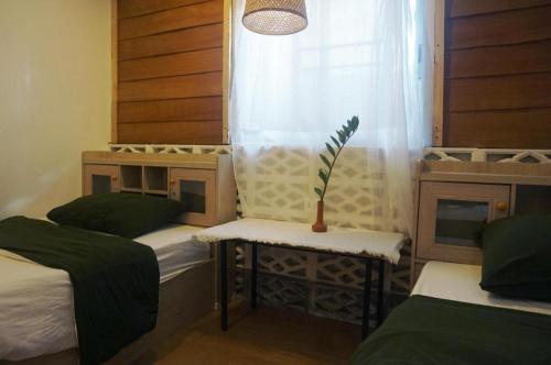 a room with two beds and a window with a plant at THE GOOSE HOUSE UBON in Ubon Ratchathani