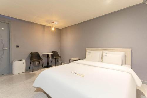 a bedroom with a large white bed and two chairs at Chuncheon World Hotel in Chuncheon