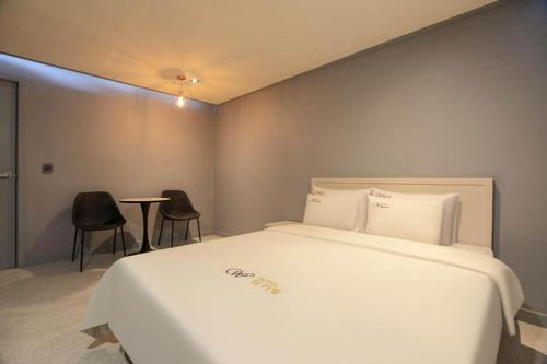 a bedroom with a large white bed and two chairs at Chuncheon World Hotel in Chuncheon