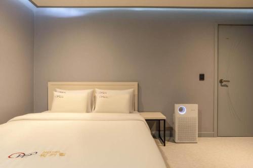 a bedroom with a large bed with white sheets and a speaker at Chuncheon World Hotel in Chuncheon