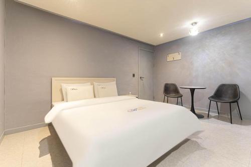 a bedroom with a white bed and two black chairs at Chuncheon World Hotel in Chuncheon
