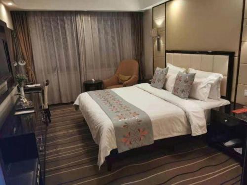 a hotel room with a large bed and a chair at Qingdao Minlian Kaixuan Hotel in Qingdao