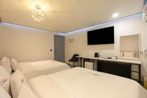 a hotel room with two beds and a desk with a television at Chuncheon World Hotel in Chuncheon