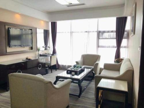 a living room with couches and a flat screen tv at Qingdao Minlian Kaixuan Hotel in Qingdao
