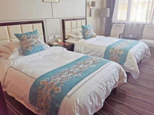 a hotel room with two beds with blue and white sheets at Qingdao Minlian Kaixuan Hotel in Qingdao