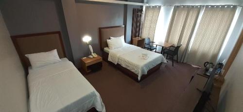 a hotel room with two beds and a table with a desk at Hotel Camila 2 in Dipolog