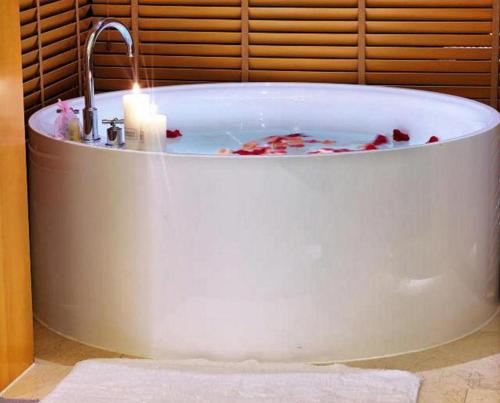 eine weiße Badewanne mit Kerzen in der Unterkunft Cixi Hangzhou Bay Hotel in Hejiao
