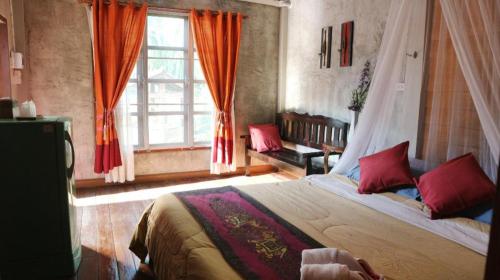 una camera da letto con un letto con cuscini rossi e una finestra di Ruen Lamai Lanna a Chiang Rai