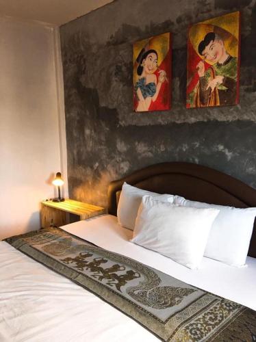 a bedroom with a bed with two paintings on the wall at Sritrang Hotel in Trang