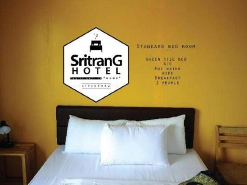 a bedroom with a bed with a sign on the wall at Sritrang Hotel in Trang
