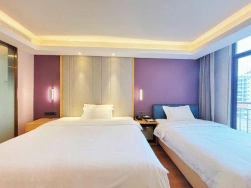 two beds in a hotel room with purple walls at Lavande Hotel·Dongxing Port in Fangcheng