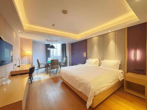a bedroom with a large white bed and a desk at Lavande Hotel·Dongxing Port in Fangcheng