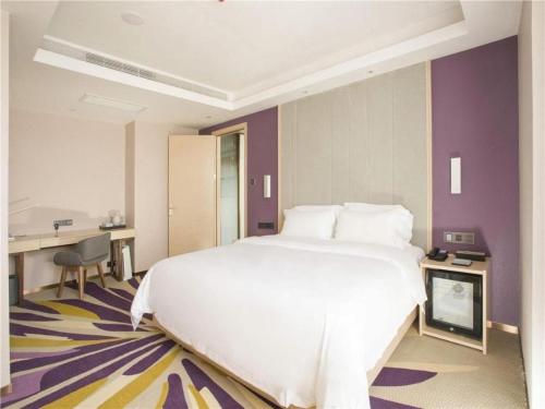 a bedroom with a large white bed and purple walls at Lavande Hotel·Dongxing Port in Fangcheng