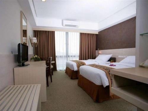 a hotel room with two beds and a television at Ratu Hotel Serang in Serang
