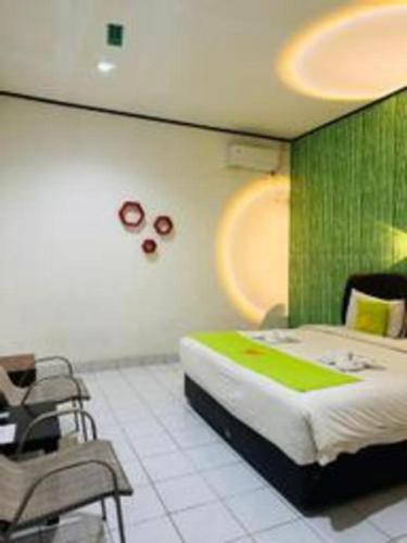 a bedroom with a large bed and chairs in it at Hotel Huswah Airport in Jakarta