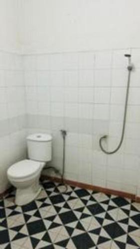 a bathroom with a toilet and a black and white checkered floor at Hotel Huswah Airport in Jakarta