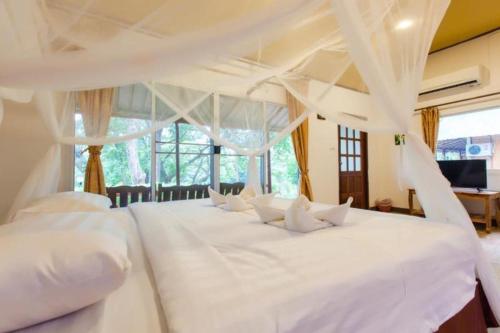 un letto bianco con cuscini bianchi in una camera da letto di Varee Valley Resort and Restaurant a Khon Kaen