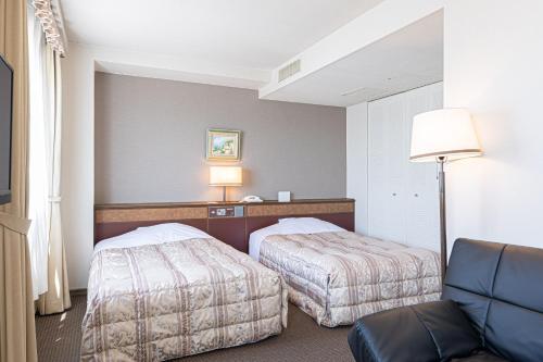 a hotel room with two beds and a lamp at GARDEN HOTEL Hanayo in Tanabe