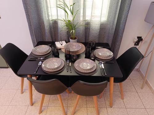 a black dining room table with chairs and plates on it at GIOLANDA PATRASSO - Modern apartment in the center of Patras in Patra