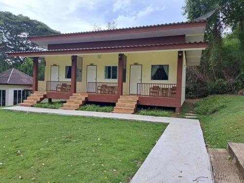 a house with a porch and a lawn at At Home Suanphung in Ratchaburi