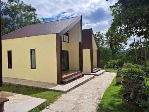 a small yellow house with a black roof at At Home Suanphung in Ratchaburi