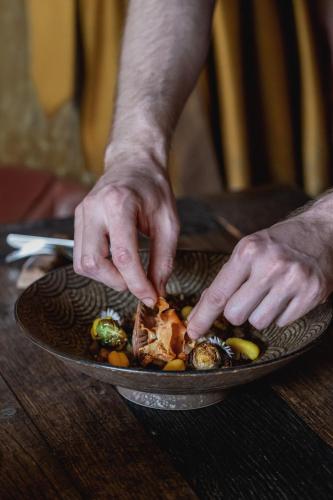 a person preparing a dish of food on a plate at Hotel Alte Post Südsteiermark in Leibnitz