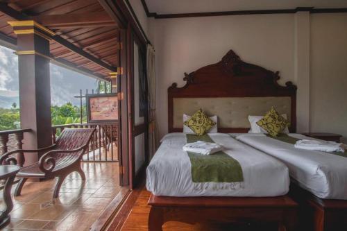 a bedroom with a large bed and a balcony at The View Pavilion Hotel in Luang Prabang