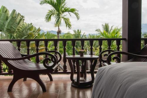 a bedroom with a balcony with a bed and a table at The View Pavilion Hotel in Luang Prabang