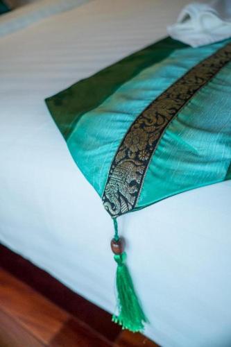 a green and black blanket on a bed at LANDMARK NAKHONPHANOM HOTEL in Nakhon Phanom