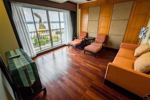 a room with a bed and chairs and a large window at LANDMARK NAKHONPHANOM HOTEL in Nakhon Phanom