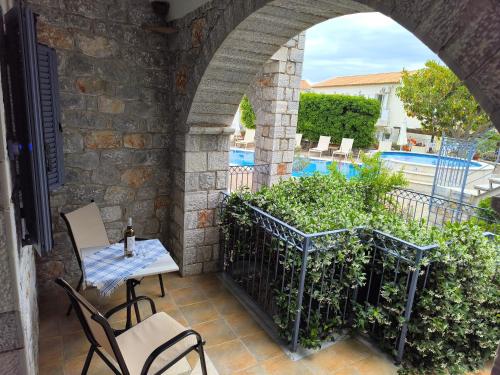 a patio with a table and chairs and a pool at Taletos Apartments in Stoupa