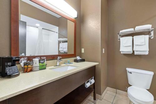 a bathroom with a toilet and a sink with a mirror at Best Western Northwest Corpus Christi Inn & Suites in Calallen