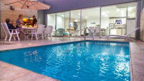 a large swimming pool with people sitting at a table at Peacehaven on Sea in Wilderness