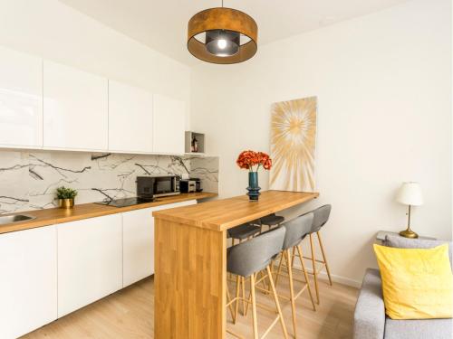 a kitchen with white cabinets and a wooden counter top at Merveil - Family Suite - Opera - Mauroy II in Paris