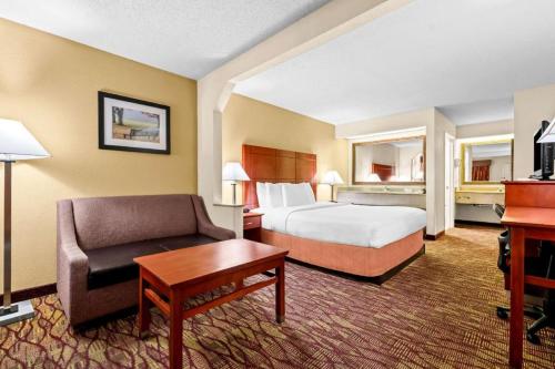 a hotel room with a bed and a couch and a desk at Best Western Inn in Clanton