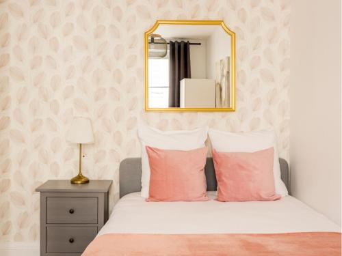 a bedroom with a bed with pink pillows and a mirror at Merveil - Family Suite - Opera - Mauroy II in Paris