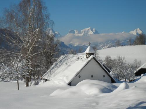 a church covered in snow with mountains in the background at Bio-Urlaubshof Dansbach in Spital am Pyhrn
